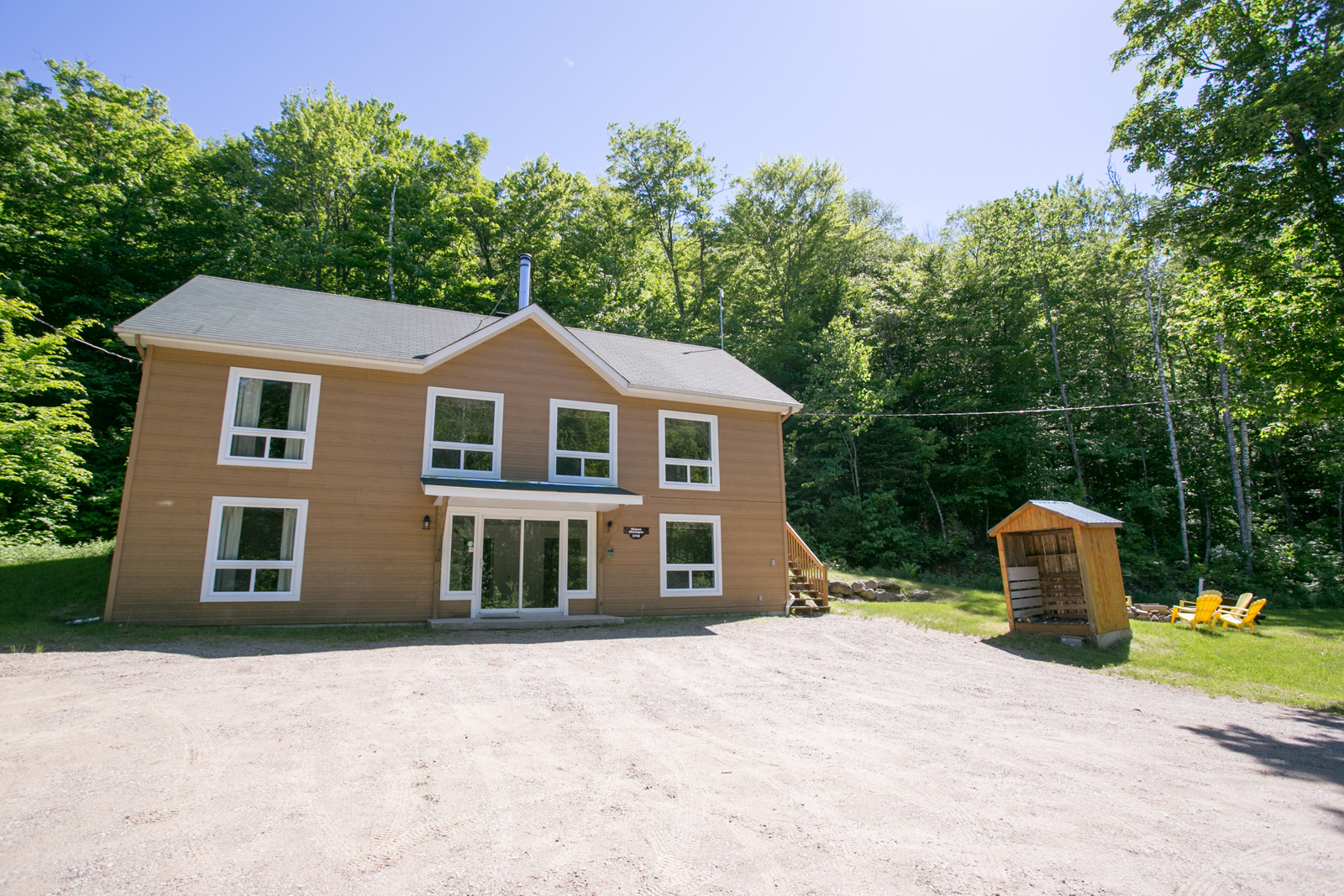 Chalet entouré d’arbres, muni de plusieurs grandes fenêtres.